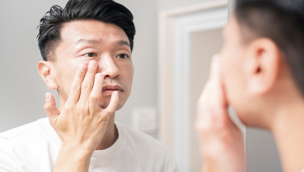 Man looking in the mirror, examining the effects of UV rays on his skin