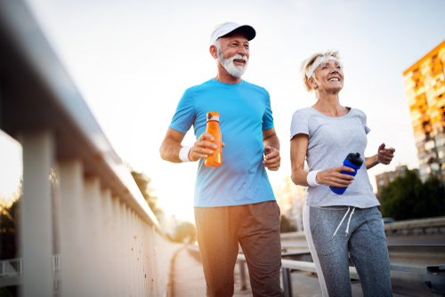 Elderly couple with water bottles practicing fall prevention strategies while running