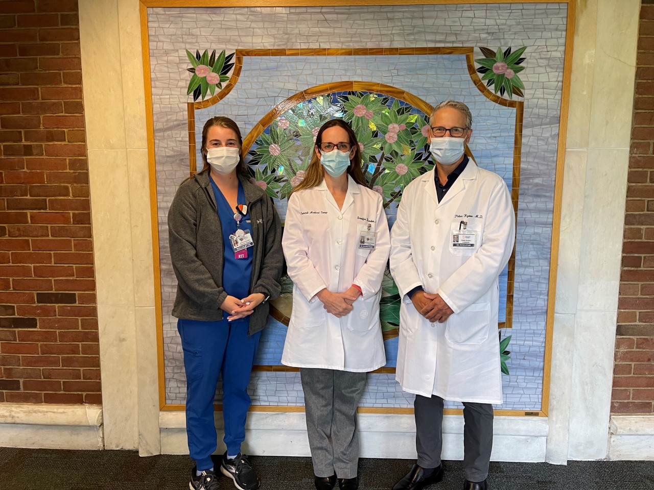 Group shot of Dr. Jennifer Reeder, radiation therapist Nicolette Slattery, and Dr. Peter Hyans in front of a colorful mosaic