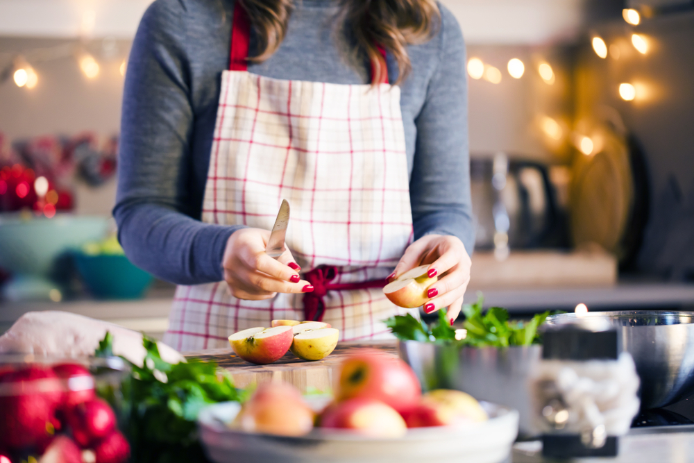 Closeup of a woman in a red and white apron slicing up an apple for a healthy holiday diet