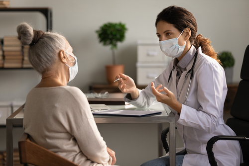 Masked female doctor explaining ways to practice good bladder health to an elderly woman