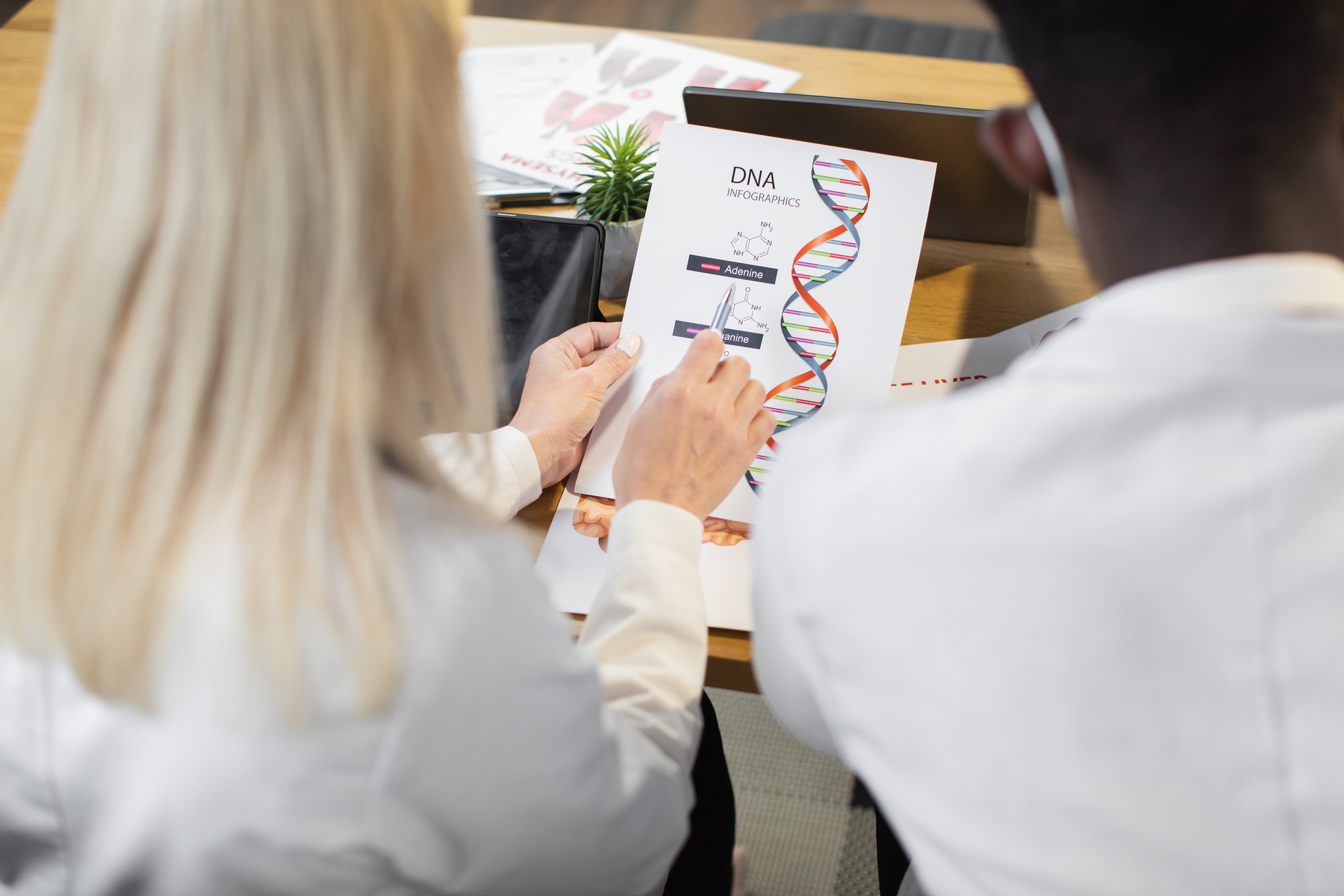 Doctor showing coworker paper with 'DNA infographics' on it to highlight rare diseases