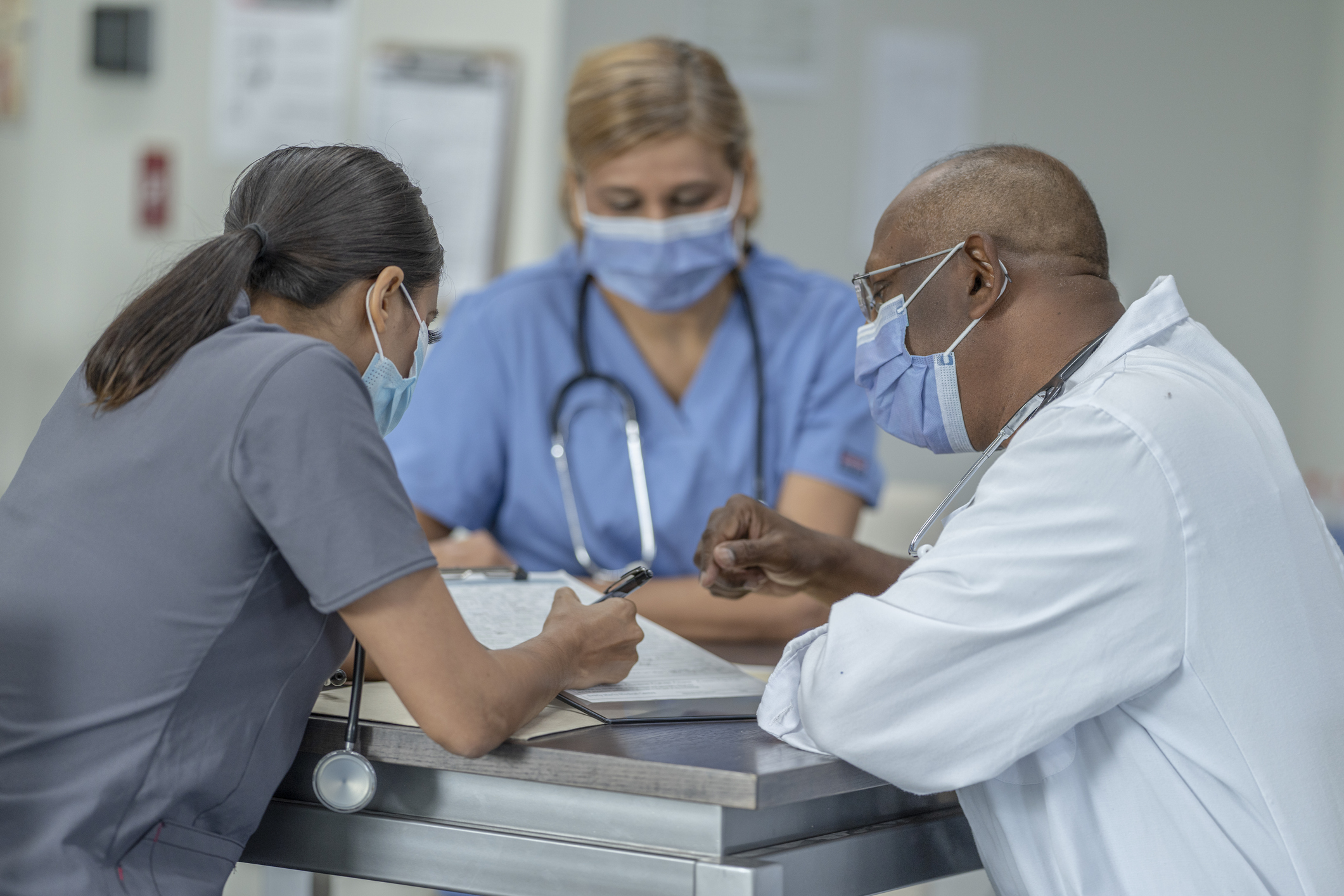 Three masked advanced practice providers going over extended health care information together as a team