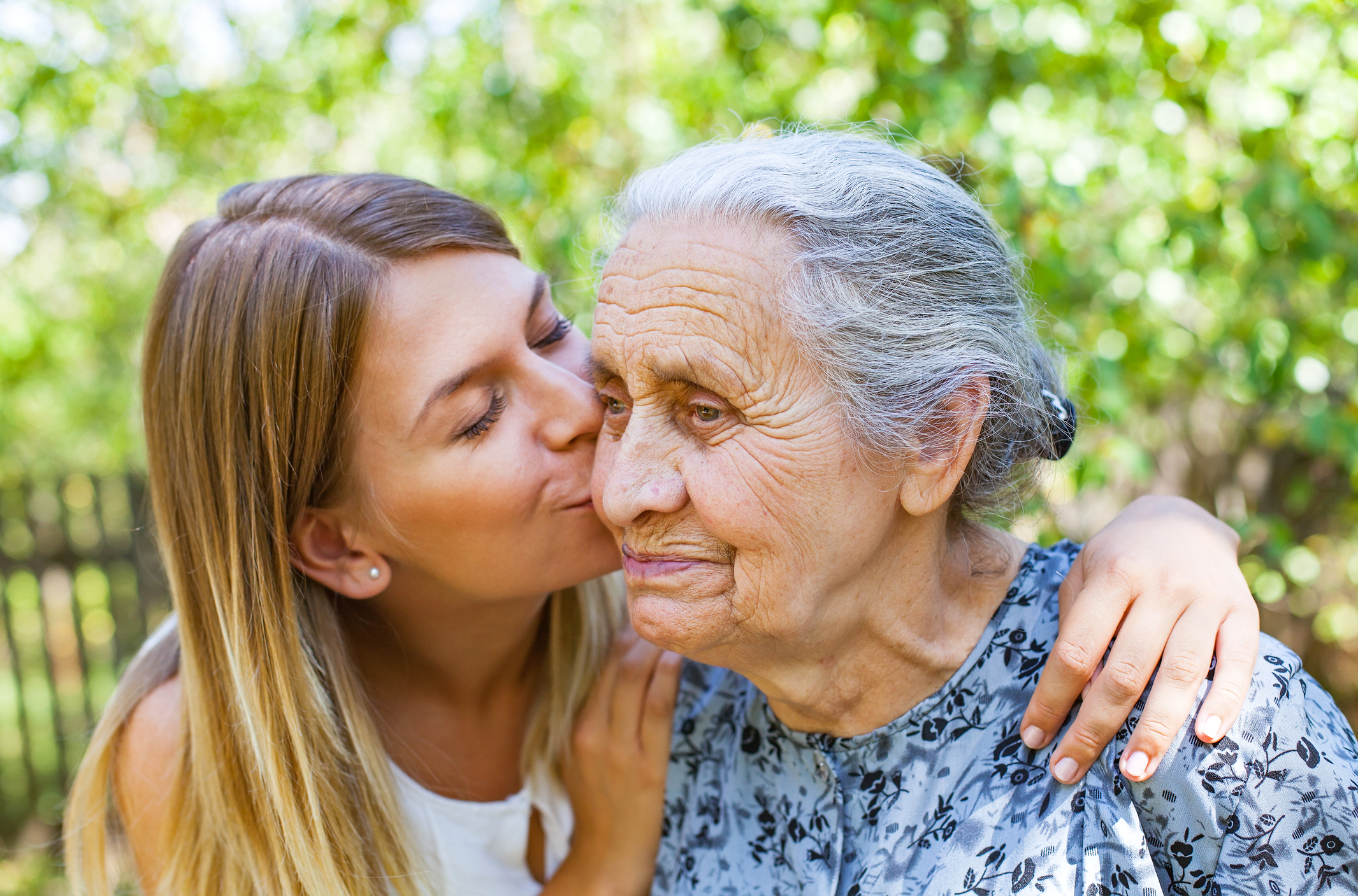 Young woman kissing an older woman with Alzheimer's disease on the cheek