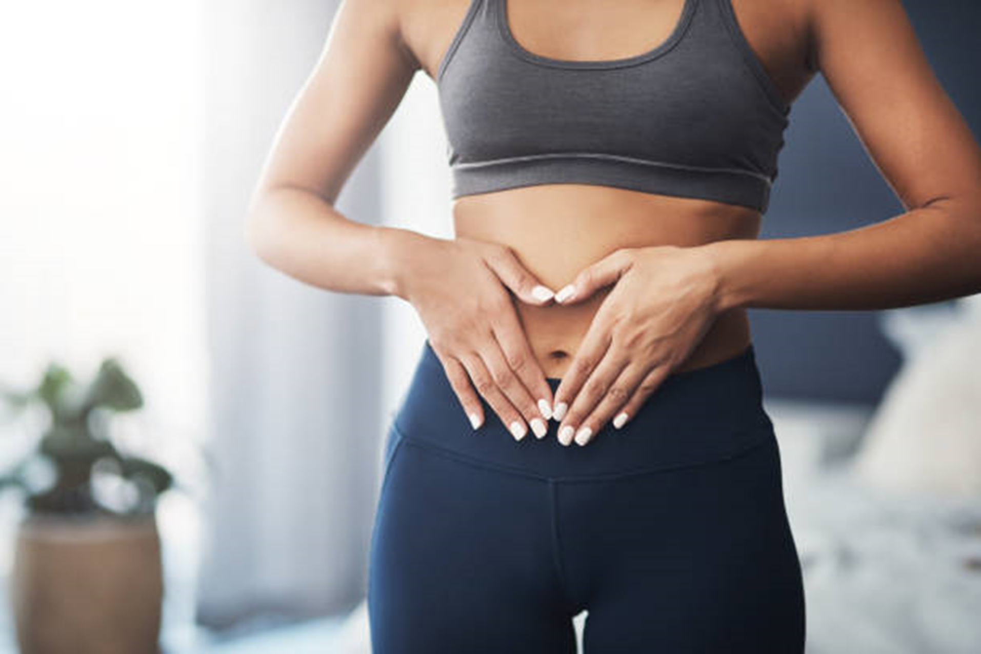 Woman touching her midsection after tummy tuck surgery in New Jersey