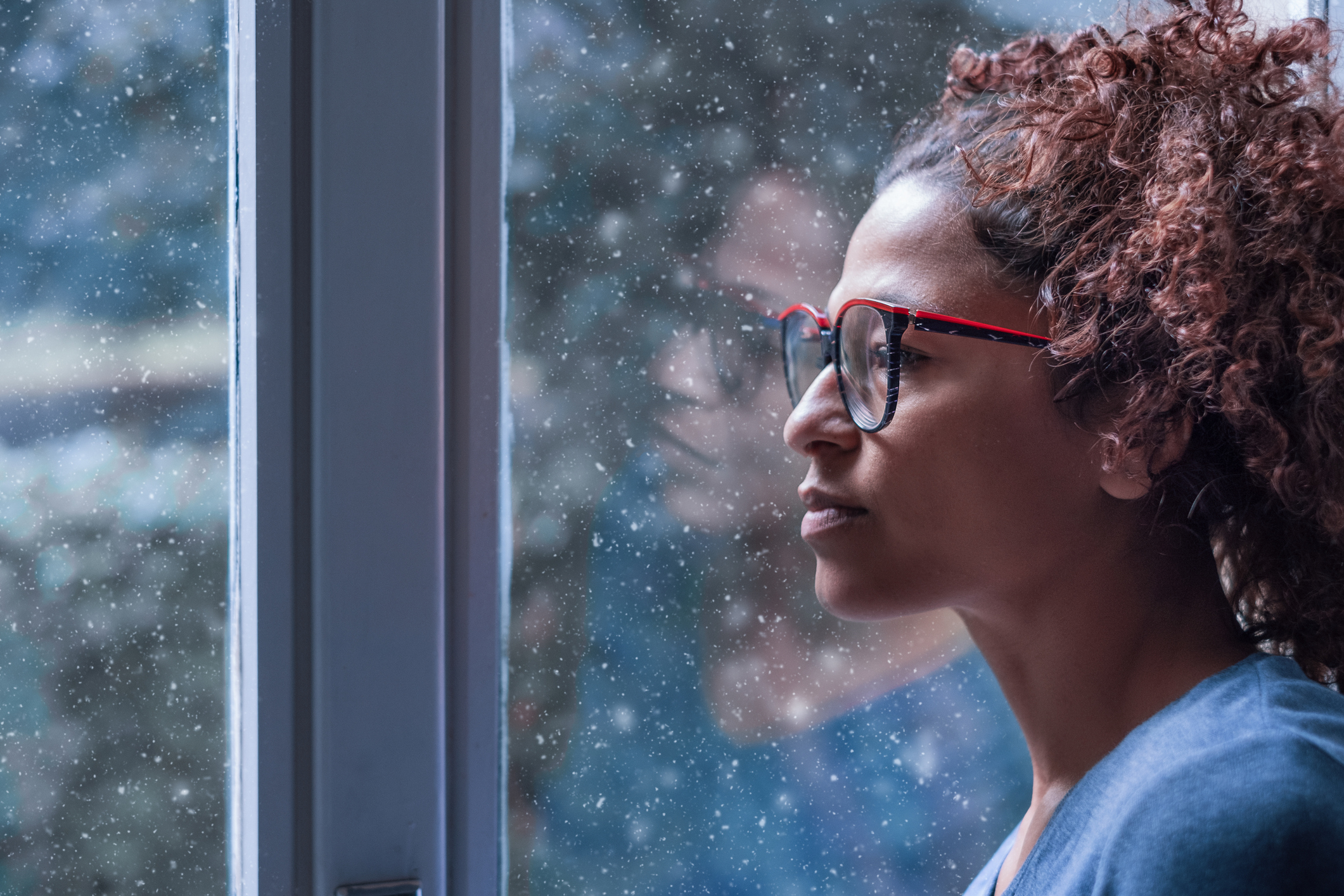 Woman with seasonal affective disorder (SAD) staring out a window. 