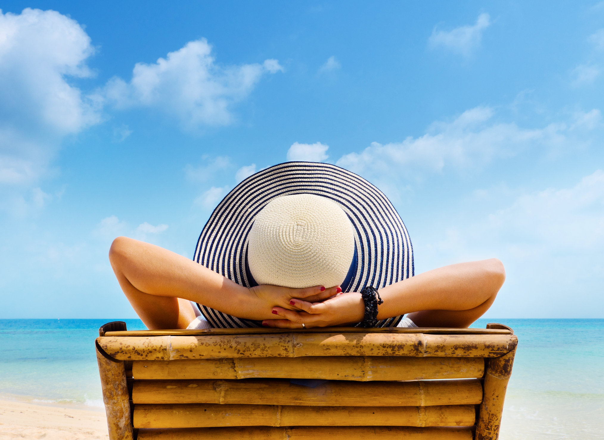 Woman in beach chair preventing sun damage with sunscreen