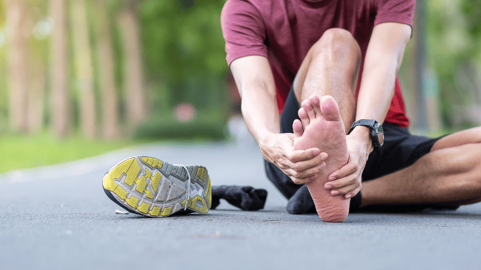 Person holding heel with visible pain, a common symptom of plantar fasciitis that can last weeks or months without treatment