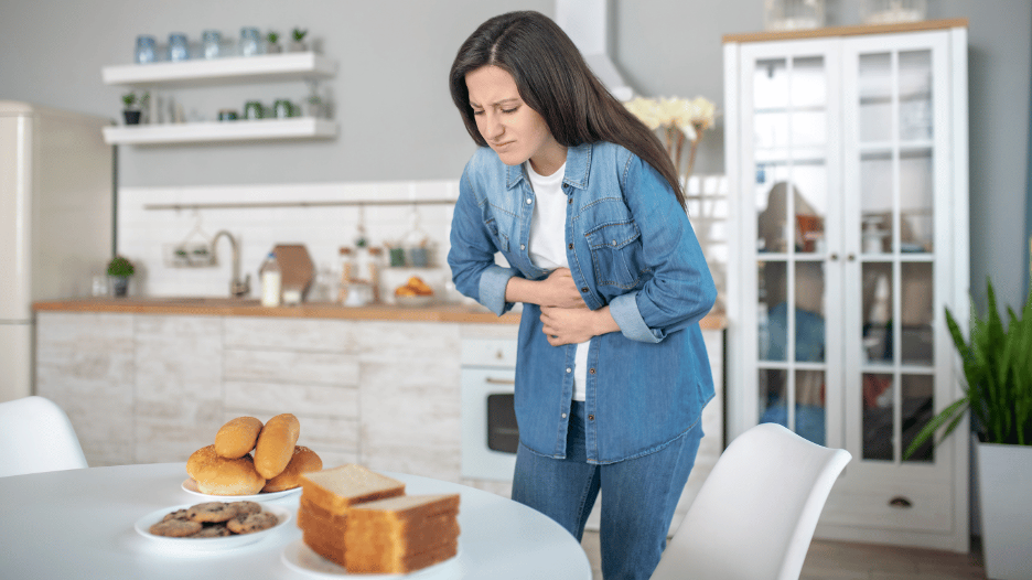 Woman grabbing her stomach in discomfort from gluten sensitivity