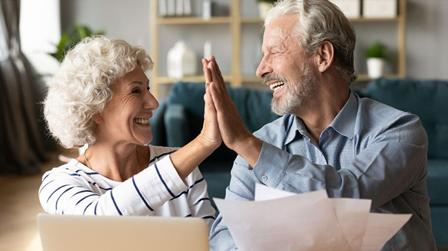 An elderly woman and man high fiving in a living room