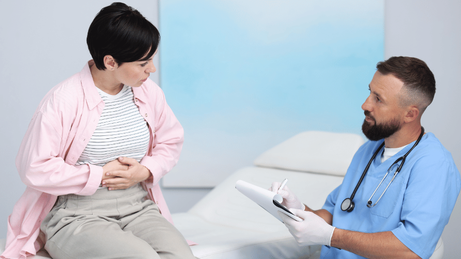Gastroenterologist discussing gastroparesis diet and digestive health treatment plan with patient holding stomach