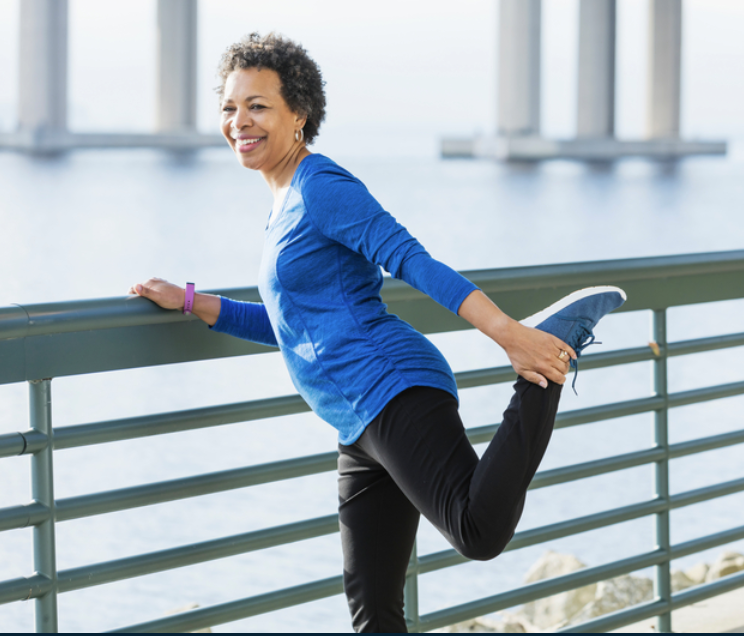 Elderly woman stretching her leg outdoors