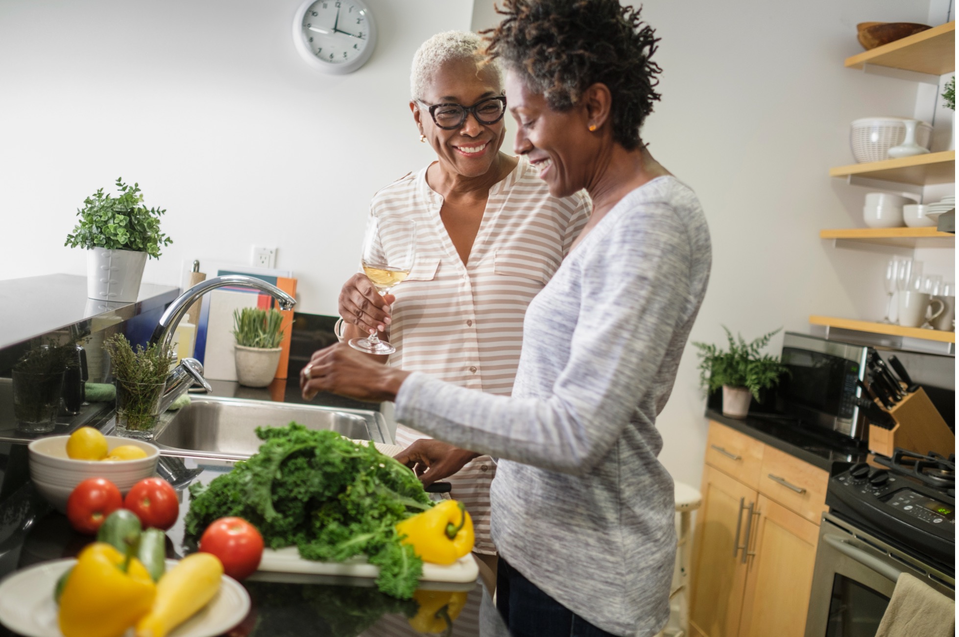 Two women smiling preparing fresh vegetables in the kitchen representing health lifestyle habits and support during menopause