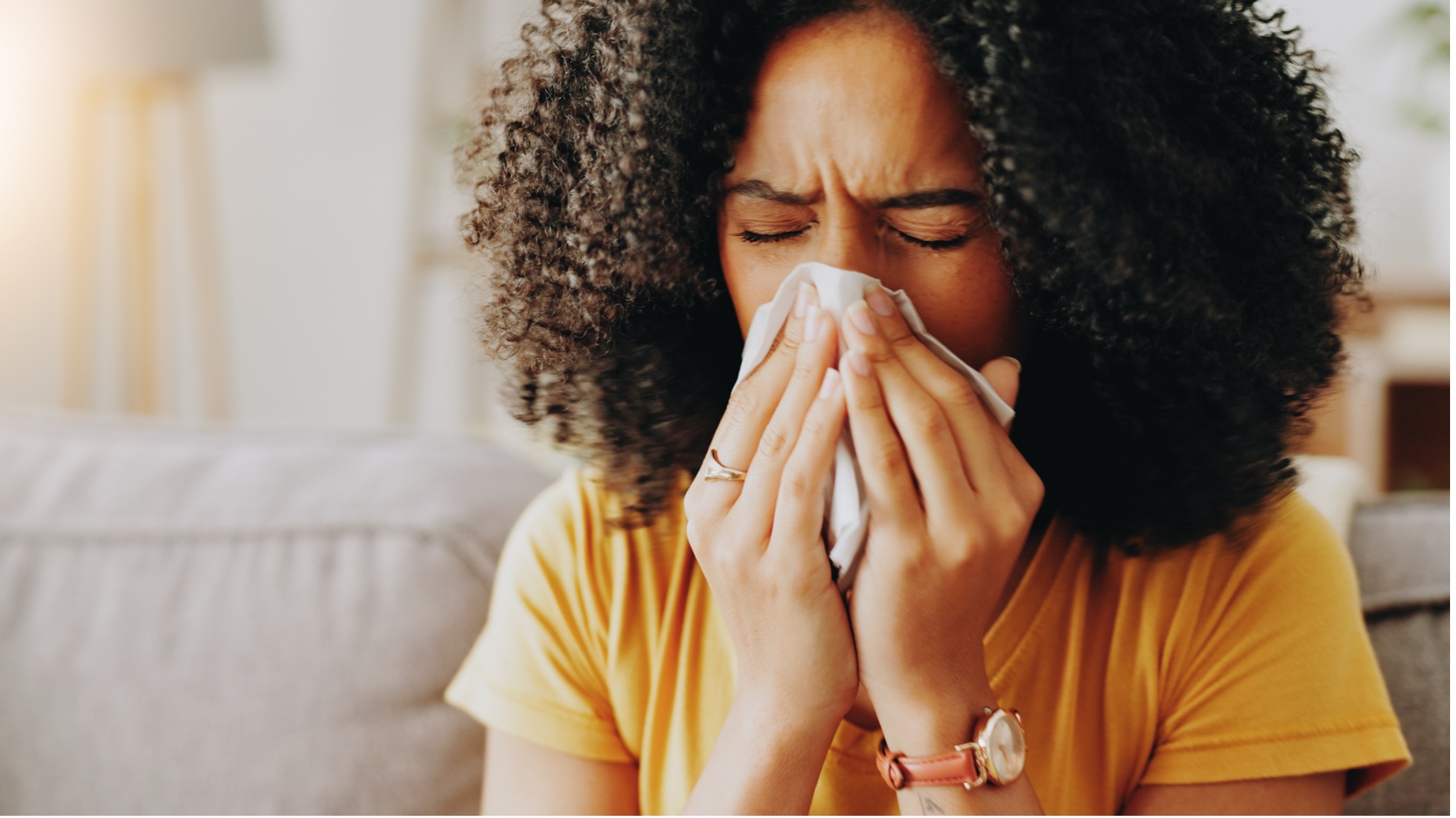 Woman blowing her nose into a tissue while experiencing sinus congestion