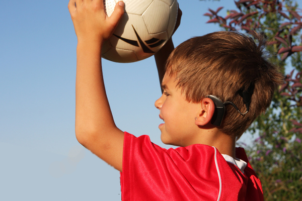boy throwing soccer ball in with ear implant