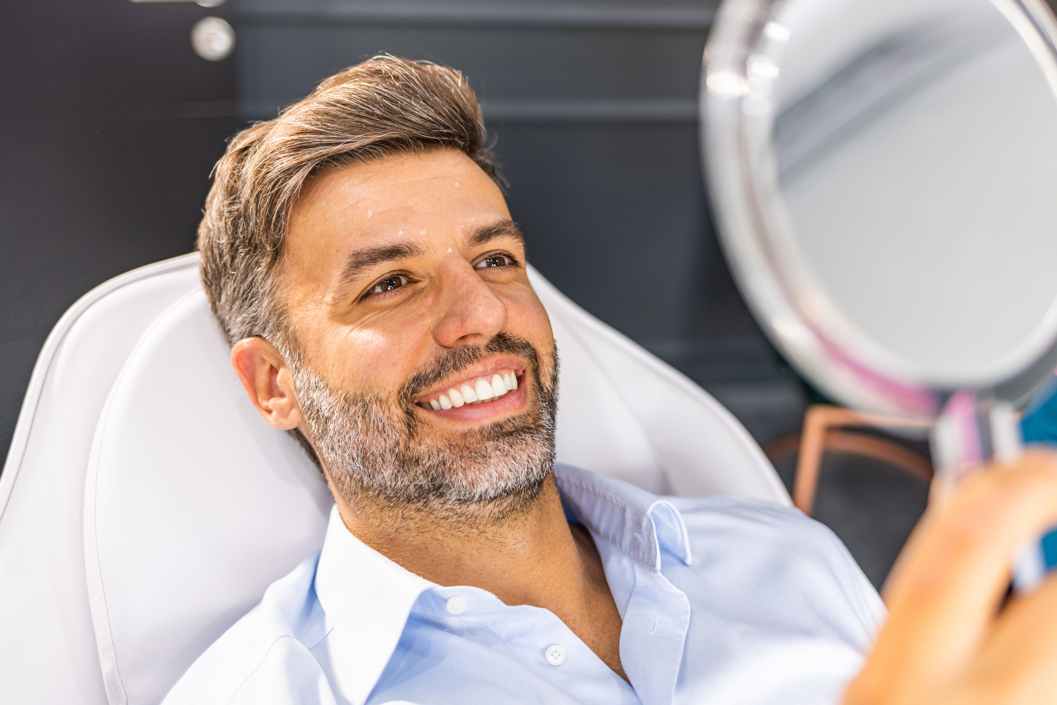 Middle aged man reviewing wrinkles in hand mirror