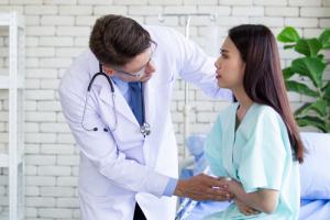 A doctor comforting a woman with IBS in blue