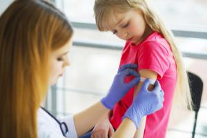 Doctor applying a bandage to a child's arm after an immunization shot