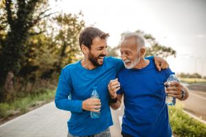 Two aging men laughing while exercising to promote healthy aging