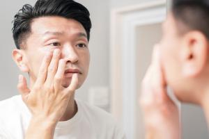 Man looking in the mirror, examining the effects of UV rays on his skin