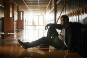 Man sitting on the floor in a school hallway
