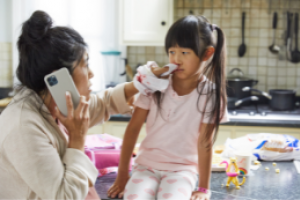Mother helping a child with a nose bleed while on the phone