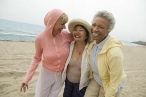Three smiling women on the beach after undergoing breast reconstruction surgery
