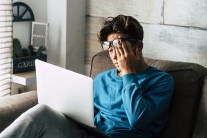 Young man at the computer rubbing his eyes after a thrown off circadian rhythm
