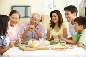 A family of six smiling and talking about their family health history around the dinner table