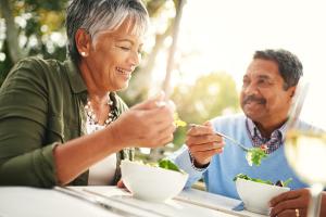 Elderly couple eating salads outside to keep their LDL cholesterol levels low