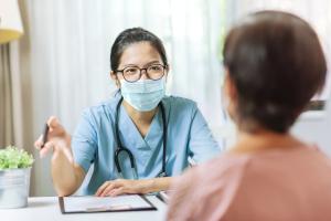 Masked doctor asking annual physicals questions to a patient