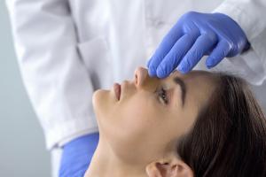 Doctor examining a woman's nose before a rhinoplasty procedure