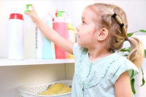 Young girl reaching for cleaning supplies that pose a poison risk