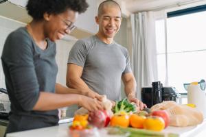 Man and woman smiling while making healthy food to improve their nutrition for colon health