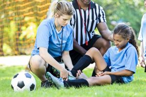 Soccer coach assisting a young girl with sports injuries
