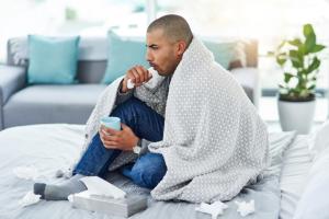 Man in a blanket on floor coughing from bronchitis