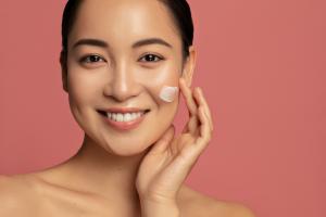 Hydration and skin care concept. Young beautiful asian model posing with applied cream on her face