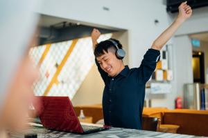 Young man stretching at computer desk after improving spine health