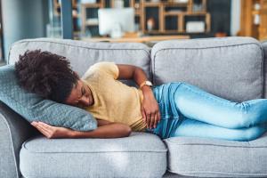 Woman on the couch feeling severe stomach pain symptoms