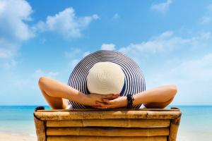 Woman in beach chair preventing sun damage with sunscreen