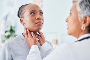 Doctor checking a woman's thyroid 