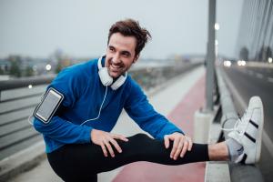 Man running outdoors stretching knee