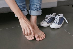 A person’s feet showing a bunion on the big toe next to improperly fitting sneakers