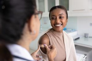 Cheerful young African patient woman visiting doctor for vaccination