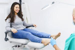Horizontal side view of brunette woman sitting on doctor's chair having a specialist appointment at medical clinic. Healthcare and medicine lifestyle.