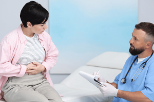 Gastroenterologist discussing gastroparesis diet and digestive health treatment plan with patient holding stomach