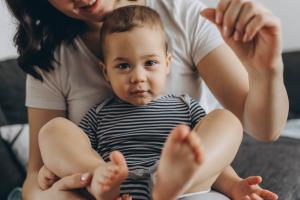 Two year old cute boy sitting in his mother arms, both smiling and enjoying a joyful moment together.