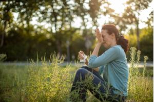 One mature woman in nature among ragweed plant suffering because she has a problem with pollen allergy at summer.