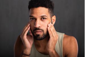 Man starting at mirror contemplating facial plastic surgery