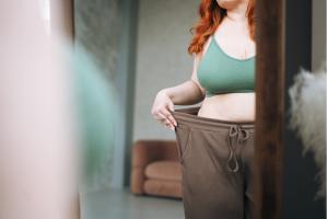 Plus size young woman in underwear looking at mirror in bedroom at home.
